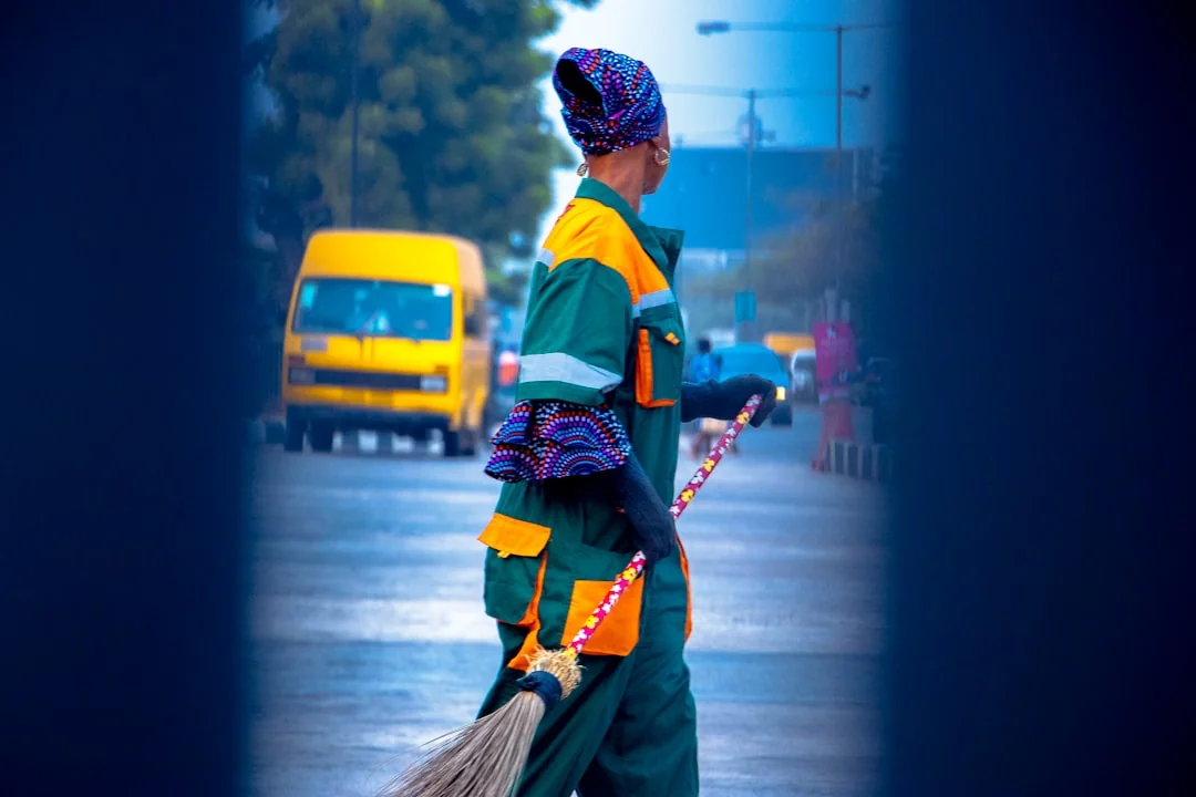 services-04 a-woman-in-a-green-shirt-and-black-gloves-vacuuming-a-gray-ottoman-5txz228u4eo